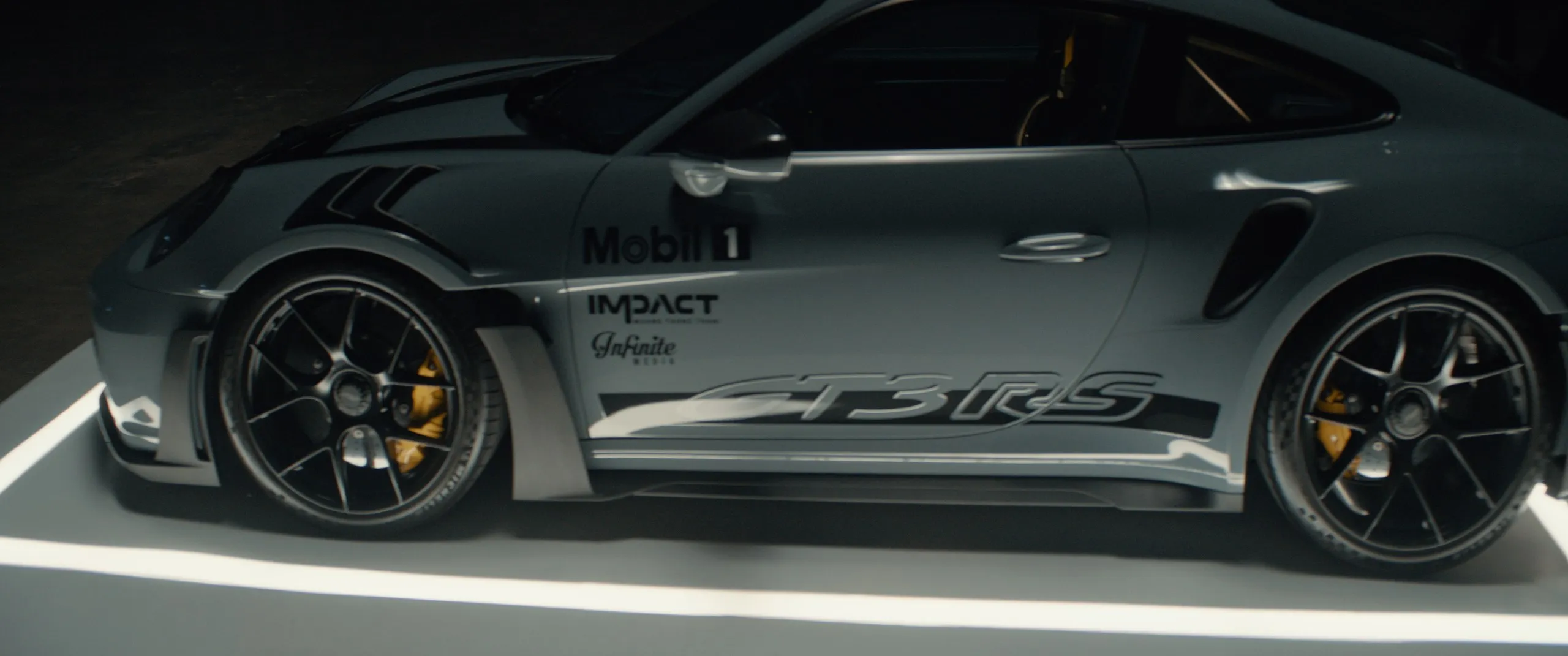 Close on the GT3 RS in Mobil 1 livery on the lit platform