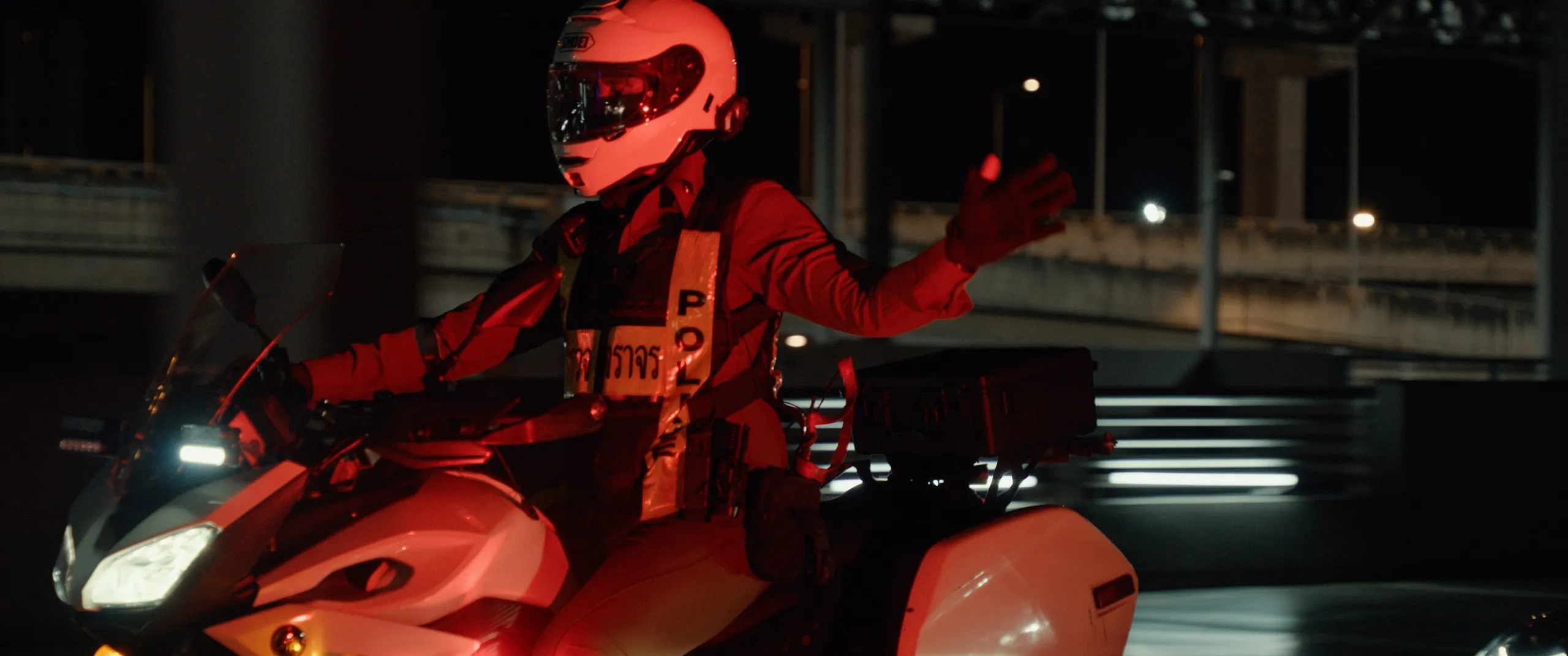 A rider in a red helmet on a motorcycle at night