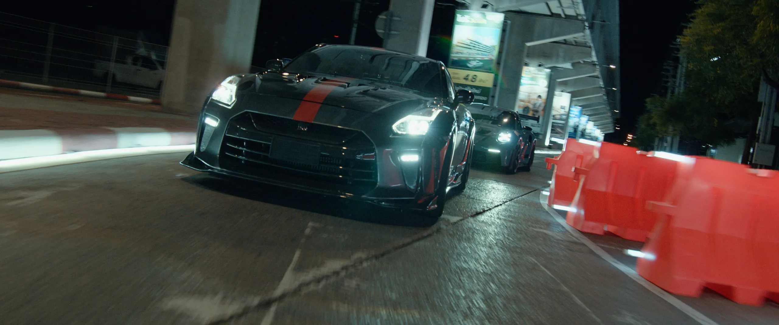 A GT-R leads through a night street circuit lined with barriers