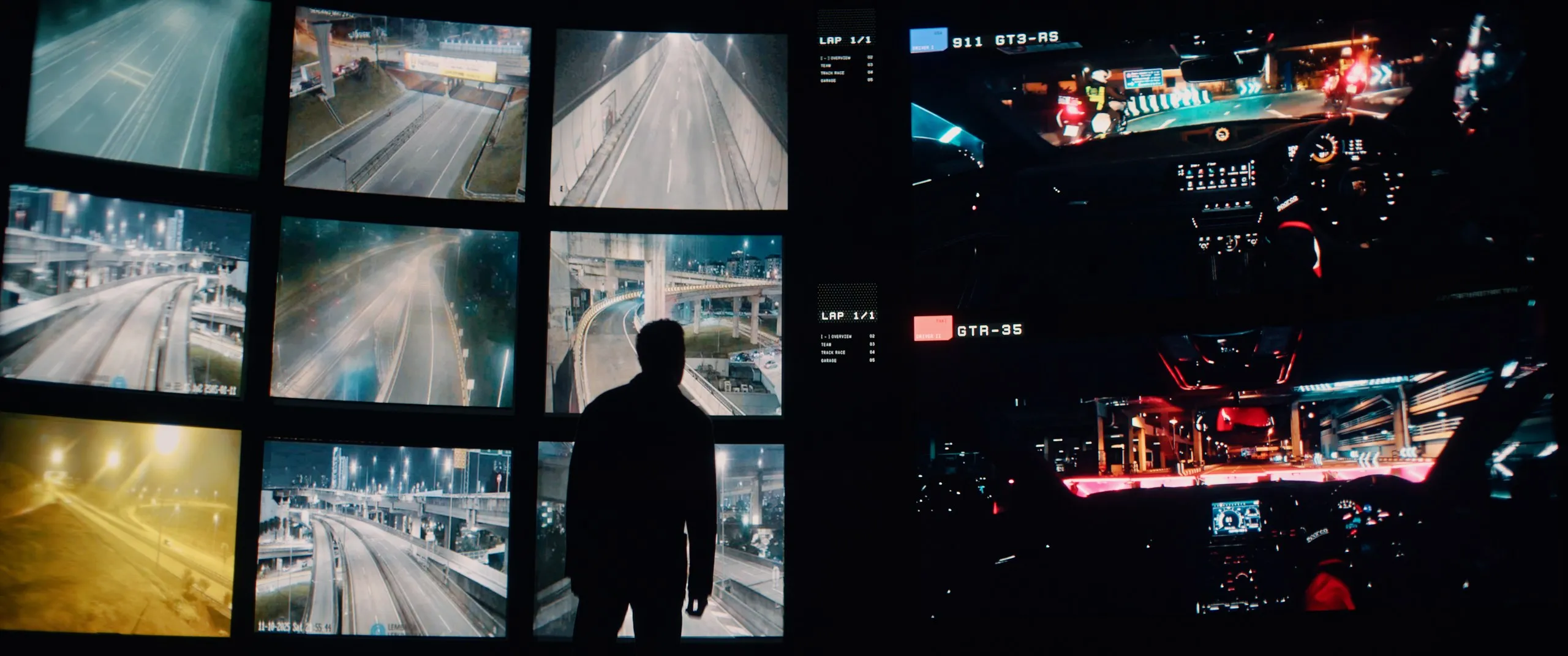 A figure in silhouette before a wall of race-feed screens