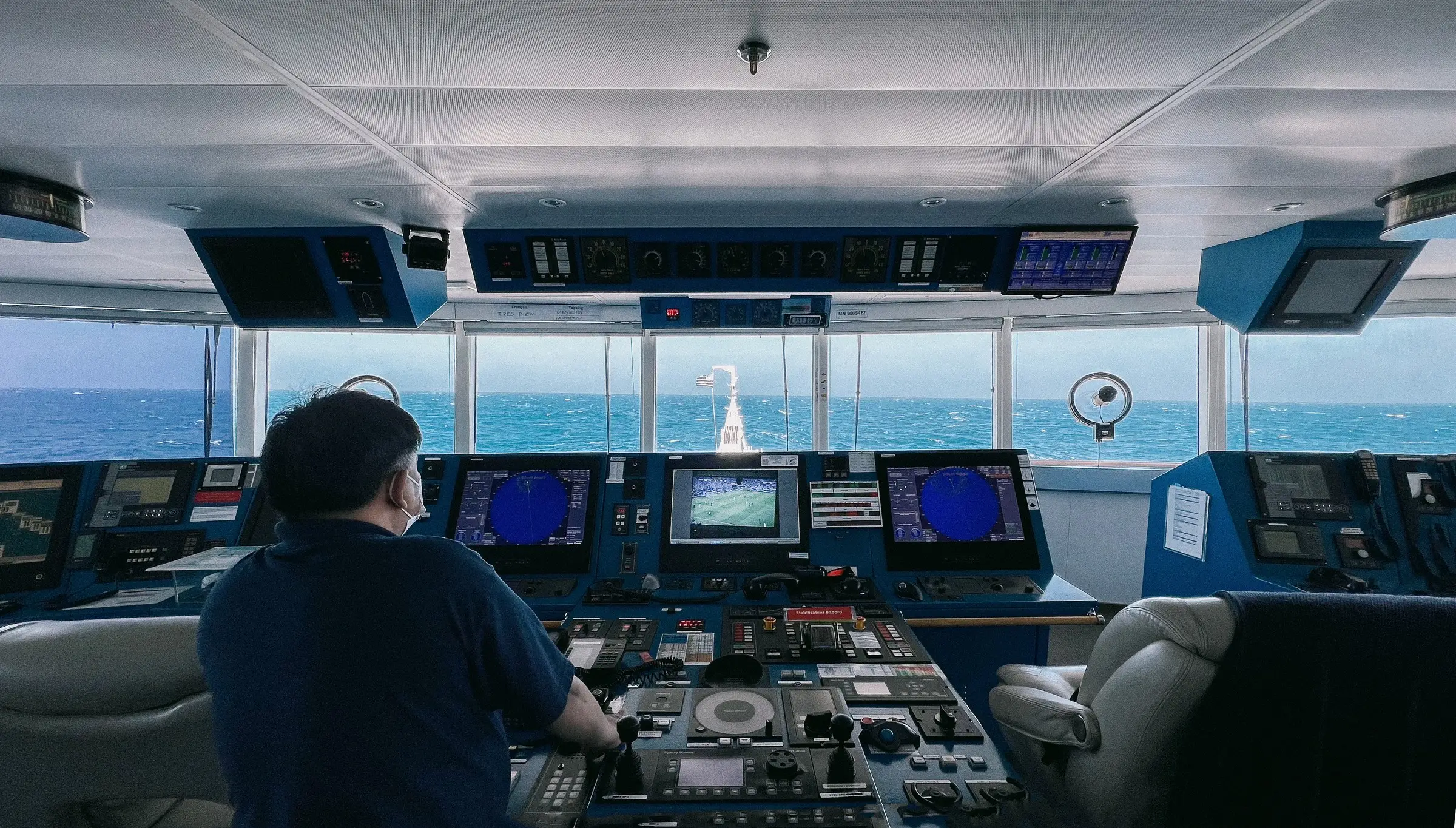 An officer on watch on a ship’s bridge, the open sea through the windows