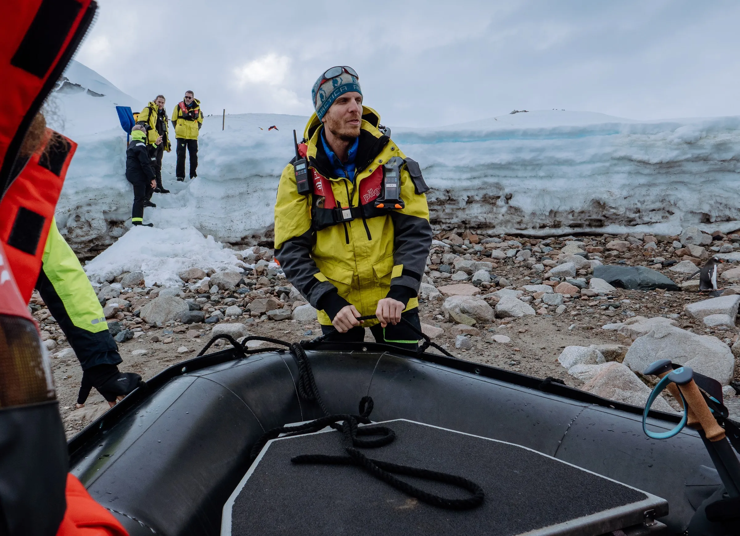 An expedition guide in a yellow jacket hauls a zodiac ashore by its bow line