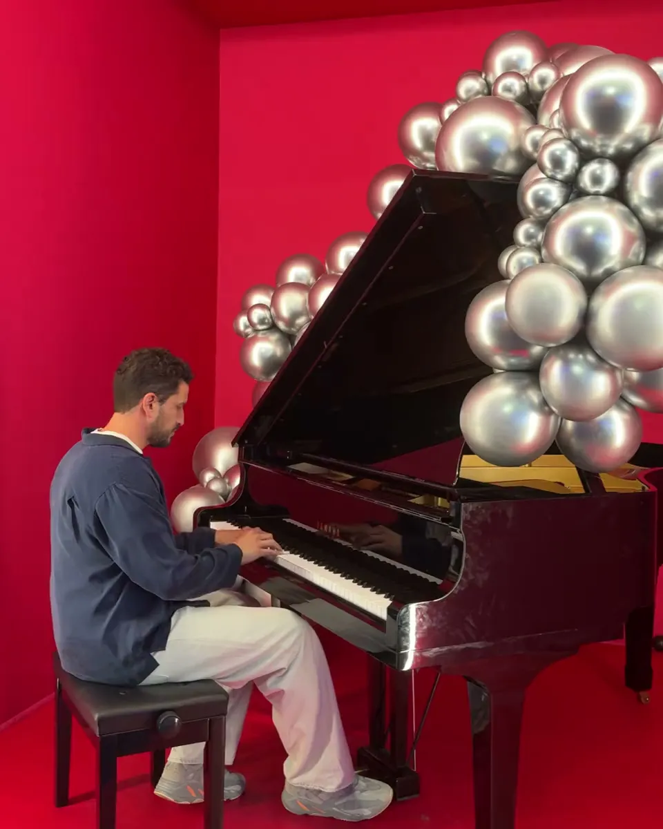 Steven Ilous playing a grand piano in a red room