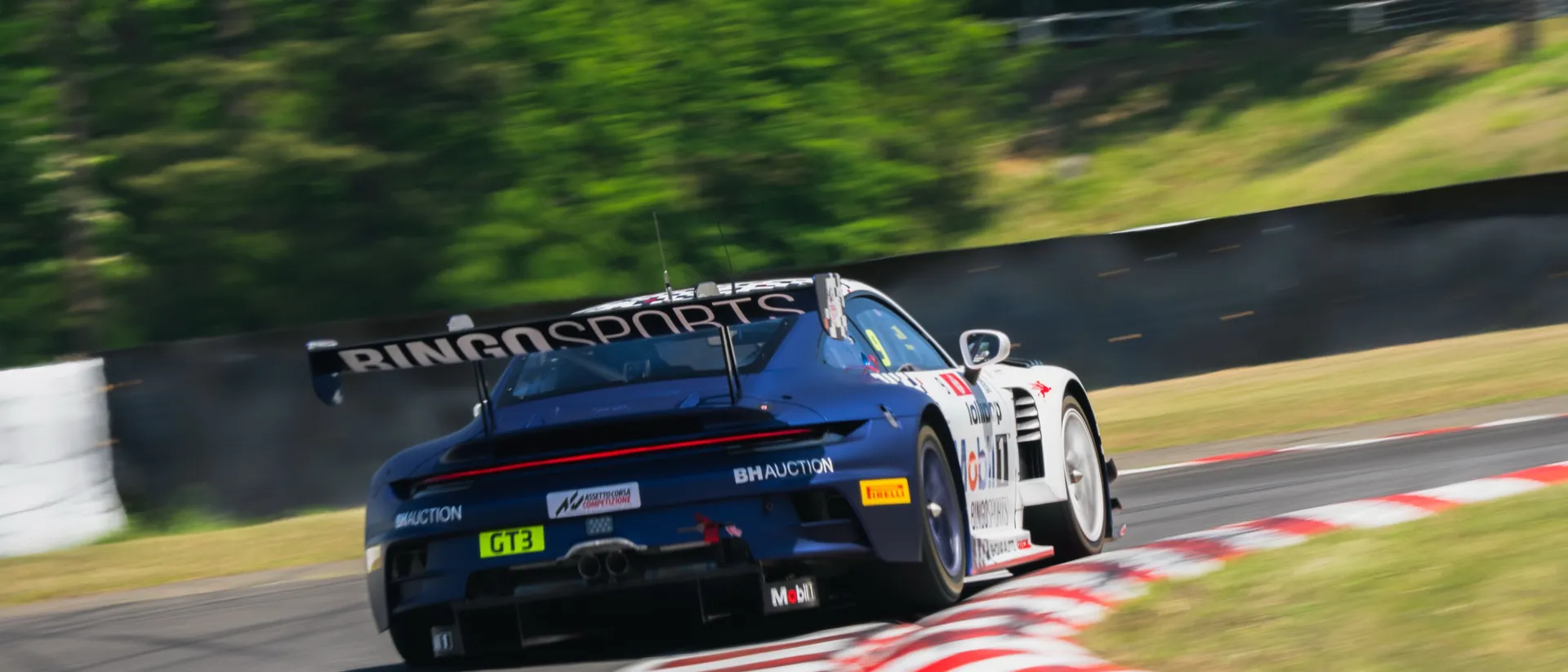 The #9 Lollipop-liveried Porsche 911 GT3 R through a corner at Sugo
